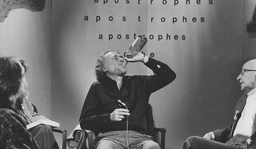 Charles Bukowski tomando de una botella en un programa de televisión